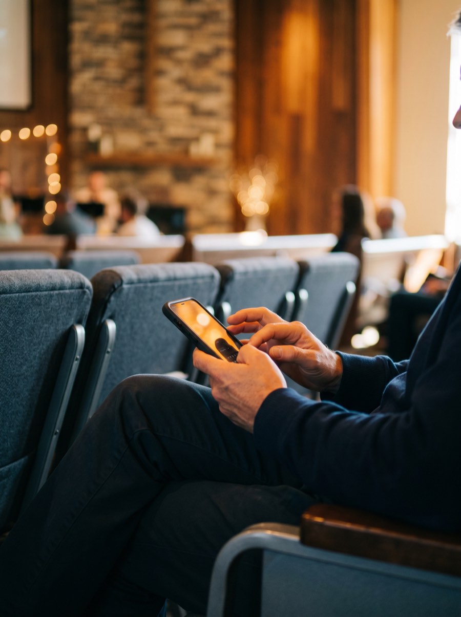 Person texting a gift on their phone in church